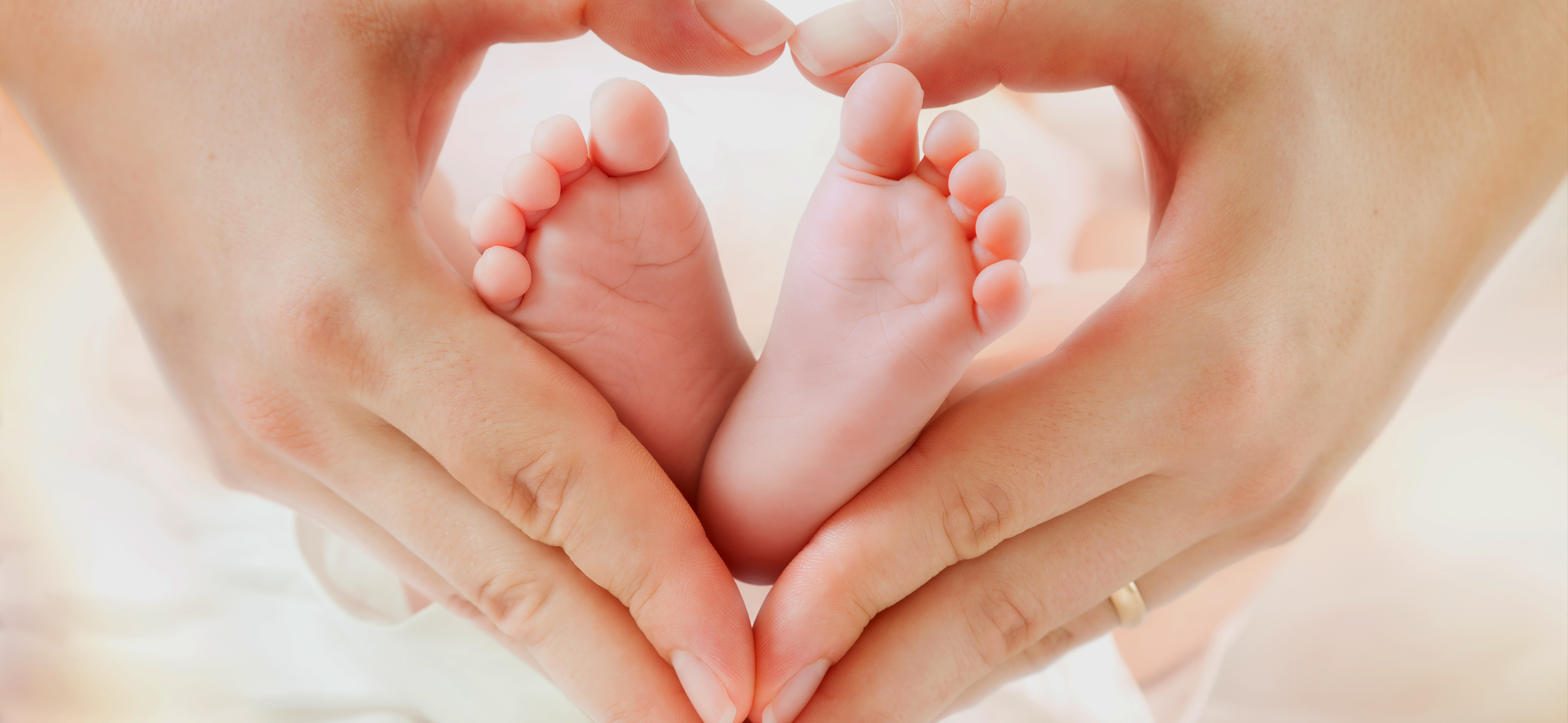 Baby-Füße in Herz geformte Hände